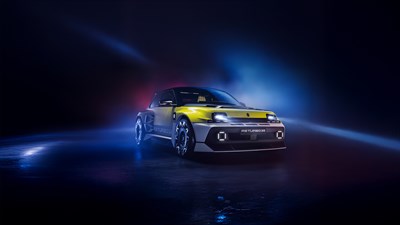 Vozilo Renault 5 Turbo 3E u dvobojnoj kombinaciji žute i crne boje osvijetljeno reflektorima na tamnoj pozadini
