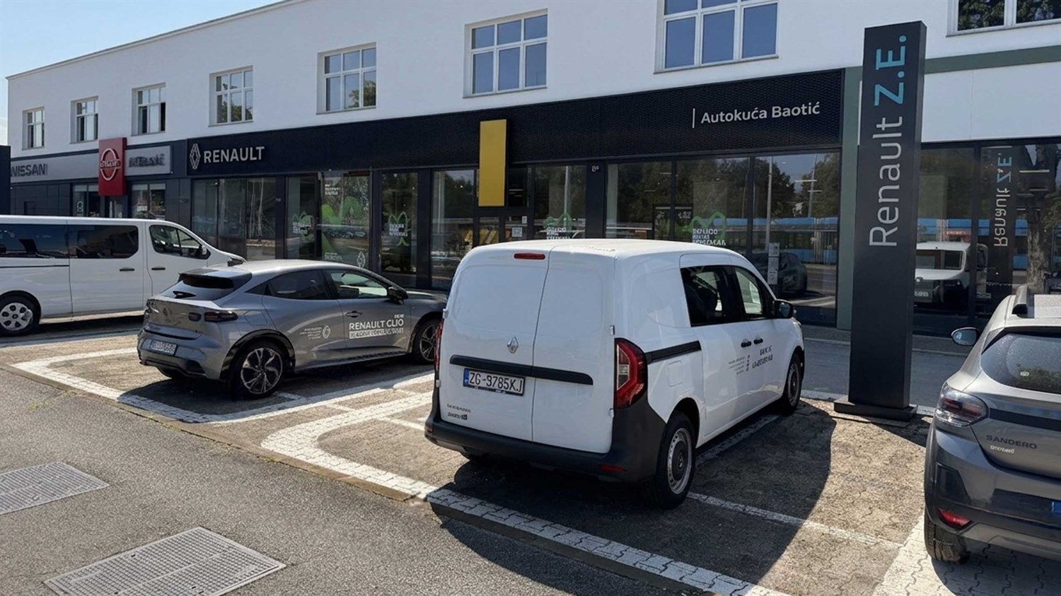 Vozilo parkirano ispred salona Renault s crnom nadstrešnicom i velikim staklenim pročeljem.