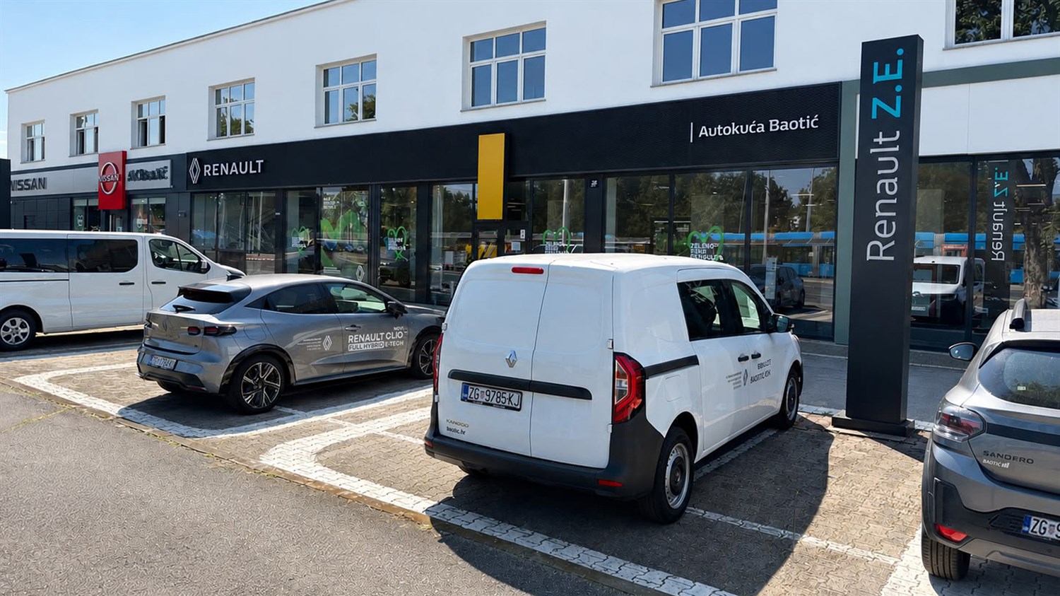 Vozilo parkirano ispred salona Renault s crnom nadstrešnicom i velikim staklenim pročeljem.