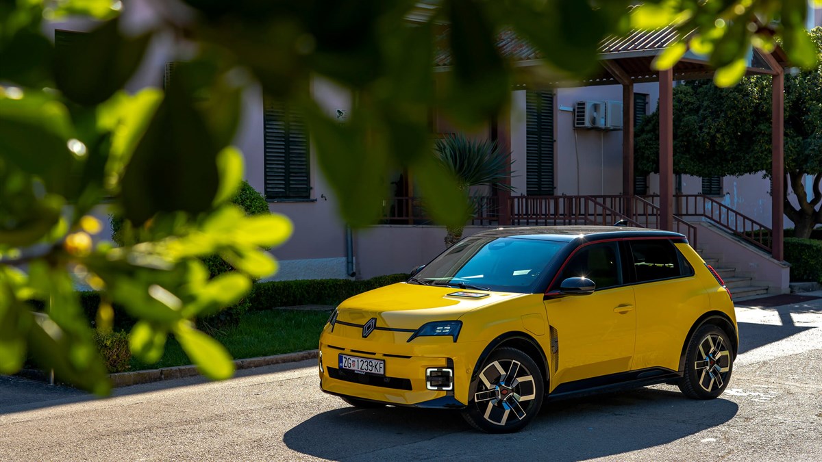 Žuti Renault 5 E-Tech electric parkiran ispred zgrade.