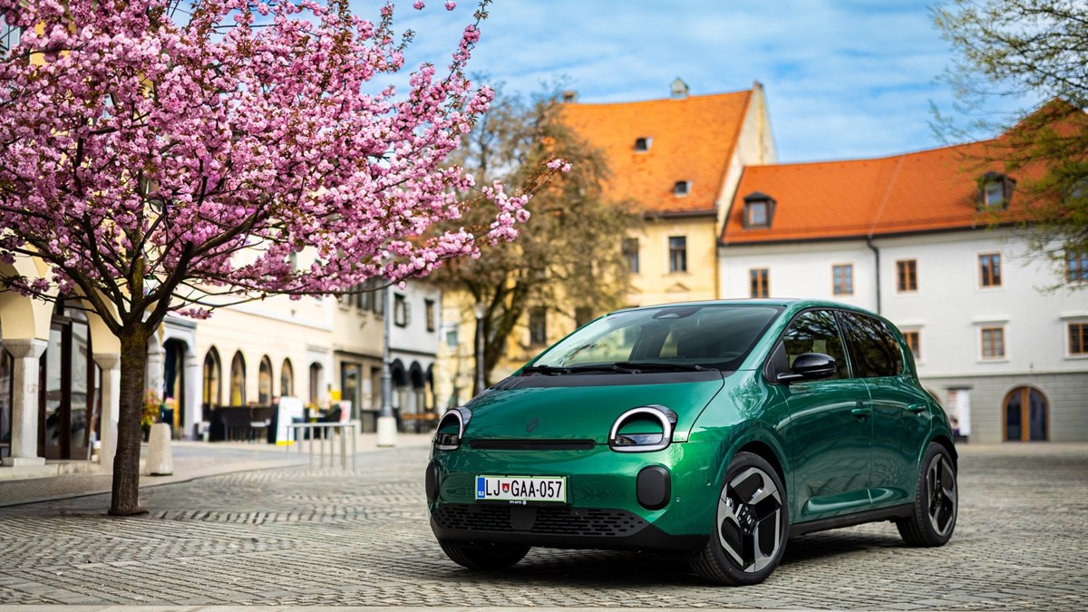 vozilo Twingo E-Tech electric parkirano na ulici uz drvorede u cvatu i obiteljske kuće