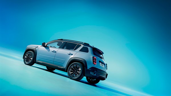 Bočni prikaz plavog SUV vozila u pokretu na svijetloj podlozi, s krovnim nosačima i aluminijskim naplatcima, na plavo-zelenoj gradijentnoj pozadini.