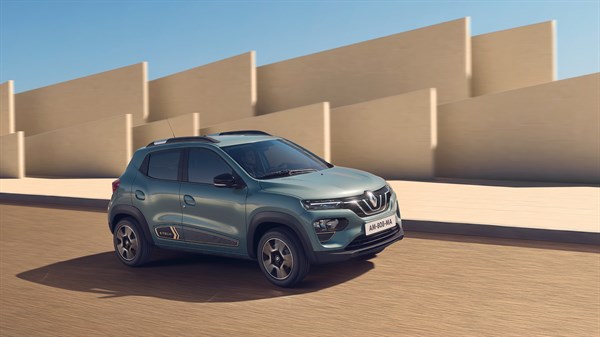Sivo vozilo Renault Kwid parkirano uz bež zidove u sunčanom ambijentu.