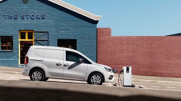 Bijelo vozilo Renault Kangoo Van parkirano ispred zgrade s modernim industrijskim izgledom.