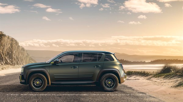 Bočni prikaz zelenog konceptnog vozila Renault Fl4wer Power Concept parkiranog uz obalu s pješčanim dinama pri zalasku sunca.