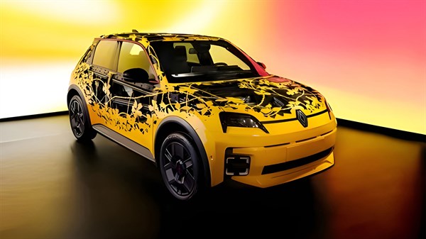 Žuto vozilo Renault s umjetničkim grafičkim uzorkom izloženo u prostoru s gradijentnom pozadinom u toplim bojama.