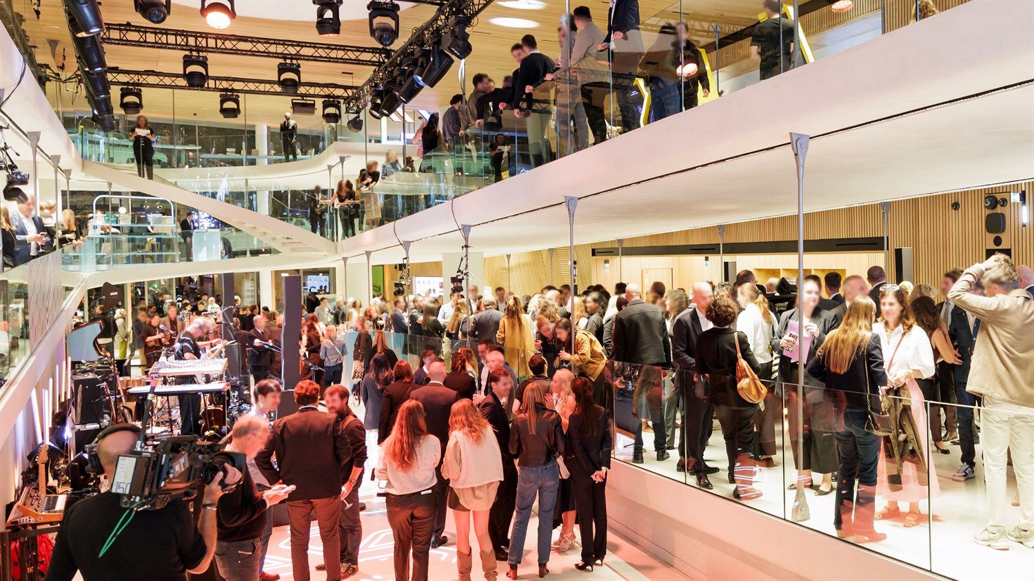 Veliki događaj u modernom izložbenom prostoru s više etaža, gdje se okuplja mnoštvo posjetitelja i medija.