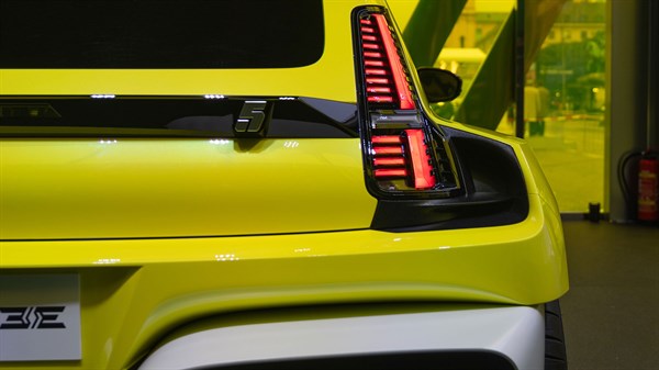 Detalj stražnjeg dijela žutog vozila Renault s upaljenim stražnjim svjetlom na izložbenom prostoru.