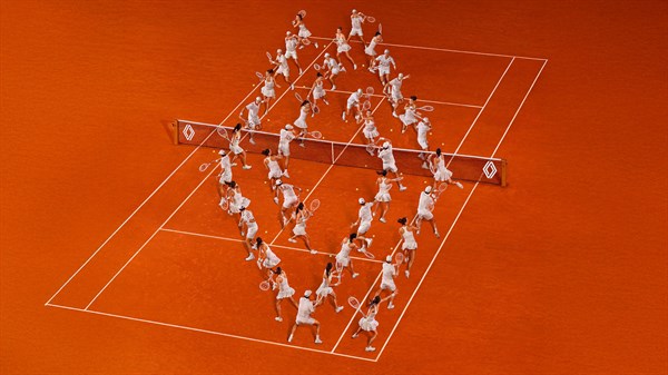 Teniski teren s igračima raspoređenima u obliku Renault dijamant logotipa na zemljanoj podlozi.