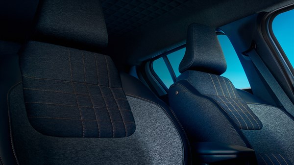 Unutrašnjost Renault vozila s prednjim i stražnjim sjedalima presvučenima tamnom tkaninom s narančastim šavovima, uz pogled na bočni prozor i plavo nebo.