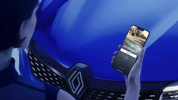 Ruka drži pametni telefon s otvorenom aplikacijom My Renault ispred plavog vozila Renault, s vidljivim prednjim dijelom i logotipom na maski.