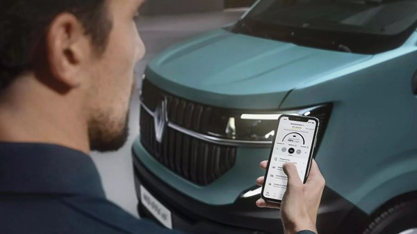 Muškarac stoji ispred zelenog vozila Renault i na pametnom telefonu pregledava digitalne korisničke upute povezane s vozilom.