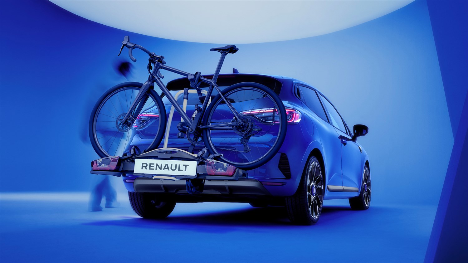 Stražnji dio vozila Clio full hybrid E-Tech s nosačem za bicikle i dva montirana bicikla u plavom studiju.-Tech full hybrid 