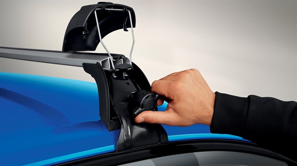 Ruka montira QuickFix krovni nosač na plavi krov vozila Clio full hybrid E-Tech, prikaz izbliza.