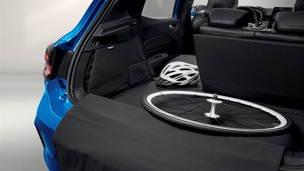 Otvoreni prtljažnik vozila Clio full hybrid E-Tech s Easyflex zaštitom i biciklističkom kacigom te kotačem unutar prtljažnika.
