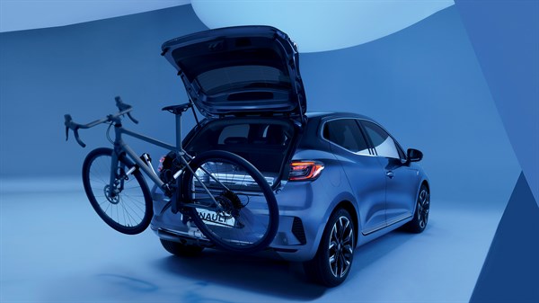 Vozilo Clio full hybrid E-Tech sa stražnje strane s montiranim nosačem na kuku za vuču i dva bicikla, prtljažnik otvoren.