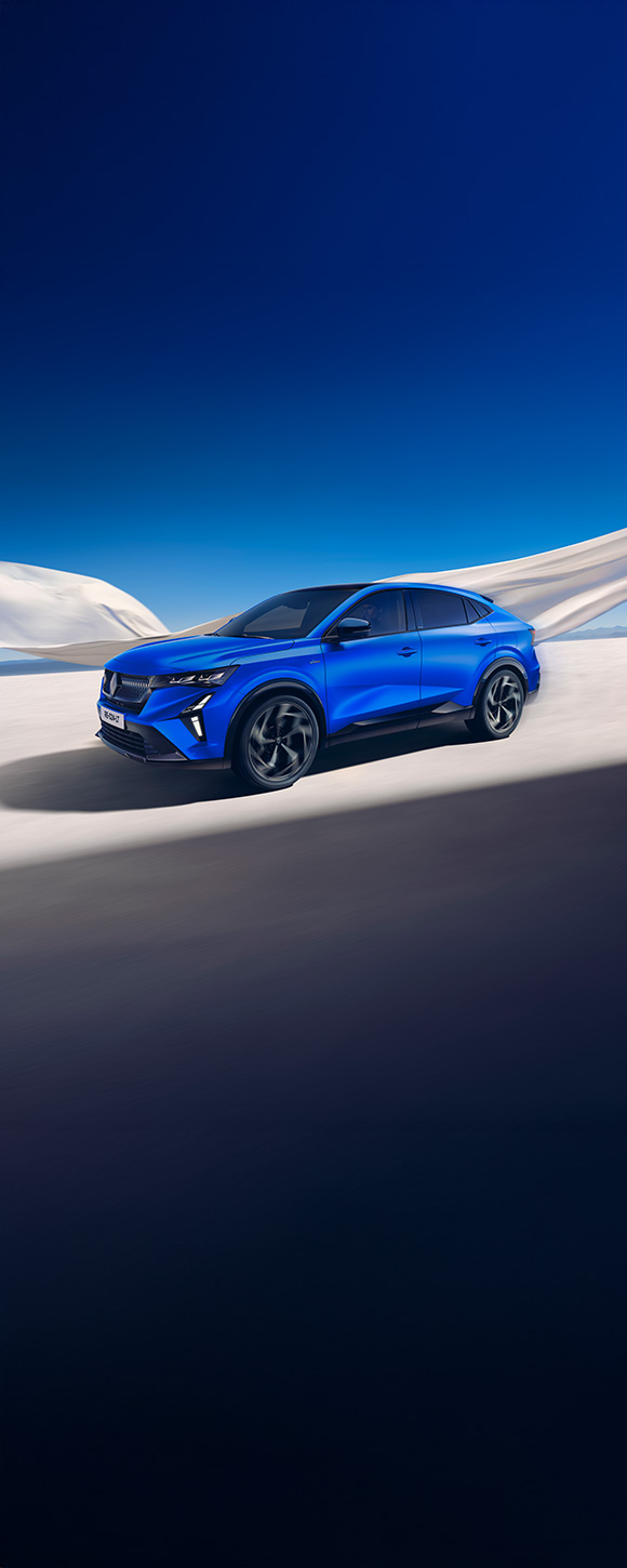 Plavi Renault Rafale E-Tech hybrid prikazan sprijeda s desne strane, parkiran u pustinji s bijelim tkaninama u pozadini.