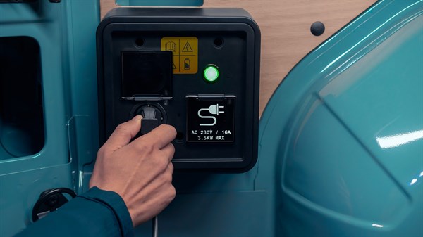 Ruka korisnika priključuje uređaj na 230V utičnicu u tovarnom prostoru vozila Renault Master