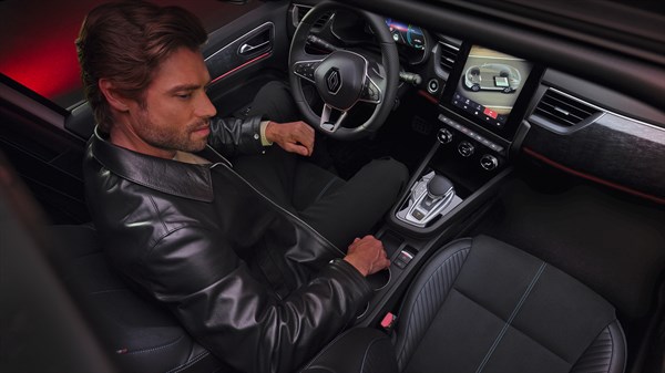 Vozač u vozilu Megane Conquest full hybrid E-Tech koristi središnji zaslon osjetljiv na dodir u modernoj kabini.


