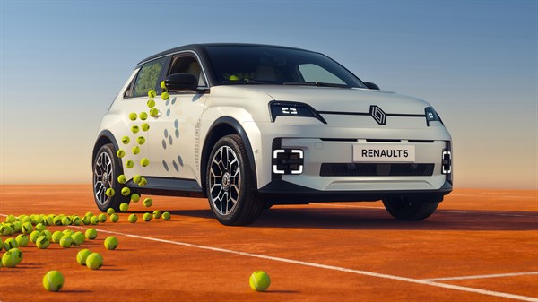 Vozilo Renault 5 E-Tech electric u bijeloj boji okruženo teniskim lopticama na narančastoj podlozi nalik terenu za tenis