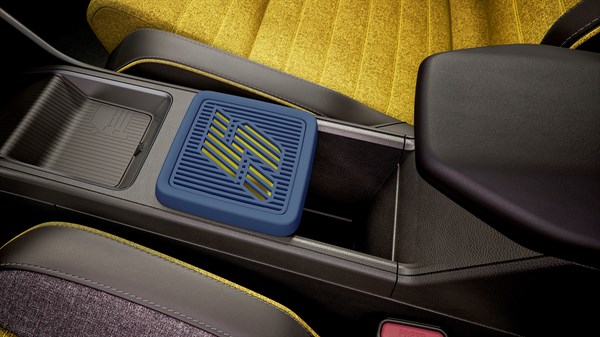 Unutrašnjost Renault 5 vozila s prikazom plave 3D printane kutije za pohranu između sjedala i naslona za ruku, na žutom tepihu