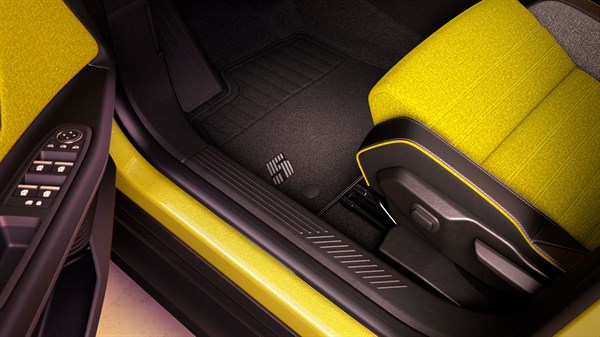 Unutrašnjost vozila Renault 5 s premium tekstilnim tepihom ukrašenim brojem 5, uz detalje sportskog sjedala u žutoj boji