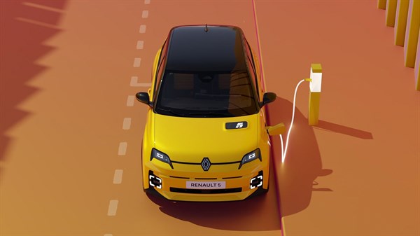 Vozilo Renault 5 priključeno na javnu AC punionicu, fotografirano sprijeda, u voznom traku sa žutim oznakama.
