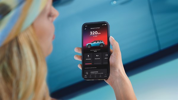 Ženska osoba drži mobitel u ruci i provjerava doseg vožnje za plavi Renault 4 E-Tech electric.
