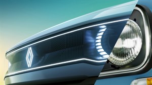 Detaljan pogled na prednji dio vozila, podijeljen na dvije polovice – lijeva prikazuje suvremeno LED osvjetljenje s osvijetljenim Renault logotipom, a desna klasični okrugli far s kromiranim rubom, što ukazuje na kontrast između modernog i retro dizajna.
