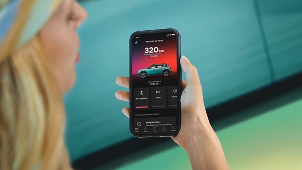 Ženska drži telefon v roki n gleda v mobilno aplikacijo, ki kaže doseg R4 vozila.
