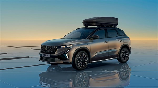 Vozilo Renault Austral full hybrid E-Tech u zlatno-smeđoj boji s krovnom kutijom, parkirano na modernoj podlozi s pogledom na zalazak sunca.
