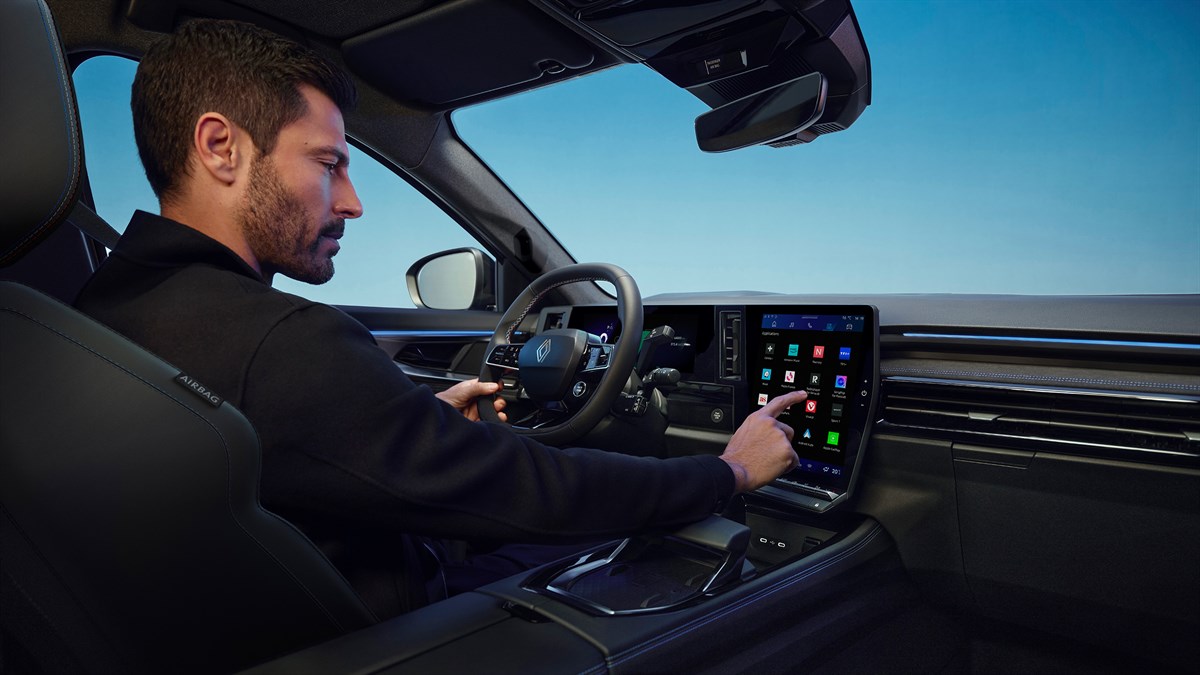 Vozač u unutrašnjosti vozila Renault koristi središnji dodirni zaslon multimedijskog sustava tijekom vožnje.