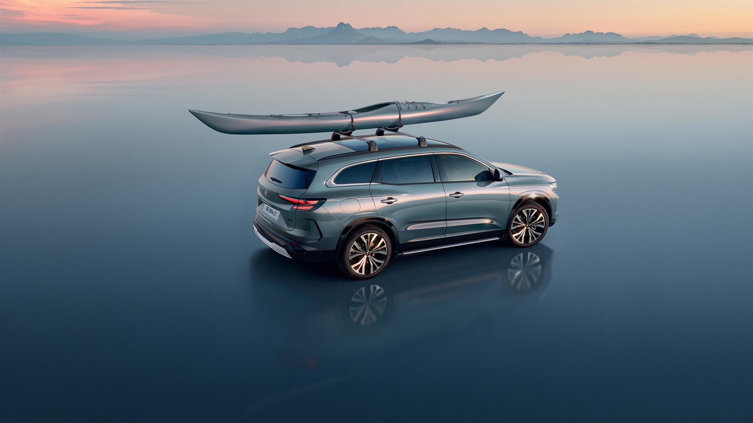 Renault Espace full hybrid E-Tech na mirnoj površini s kajakom pričvršćenim na krovne nosače.

