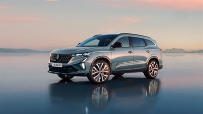 Vozilo Renault Espace full hybrid E-Tech parkirano na mokroj površini uz zalazak sunca.

