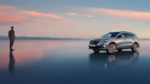 Muškarac u odijelu stoji na glatkoj reflektirajućoj površini kraj SUV vozila Renault Espace. U pozadini su planine i nebo s nježnim ružičastim oblačcima pri zalasku sunca. 