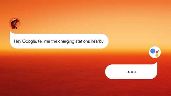 Zaslon s porukom "Hey Google, tell me the charging stations nearby" u narančastoj pozadini s Google asistent ikonom.

