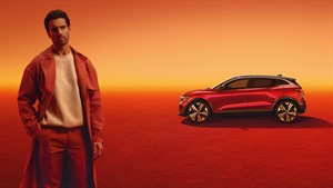 Muškarac stoji pokraj vozila Megane E-Tech electric u narančastom ambijentu.

