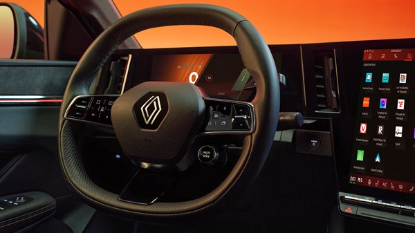 Unutrašnjost Megane E-Tech electric s fokusom na upravljač i veliki središnji zaslon, prikazana u toplom narančastom svjetlu.








