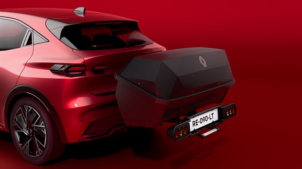 Stražnji dio vozila Renault Clio prikazan s Renault aero cargo box™ kutijom postavljenom na platformu na kuku za vuču, u crvenom studijskom okruženju.