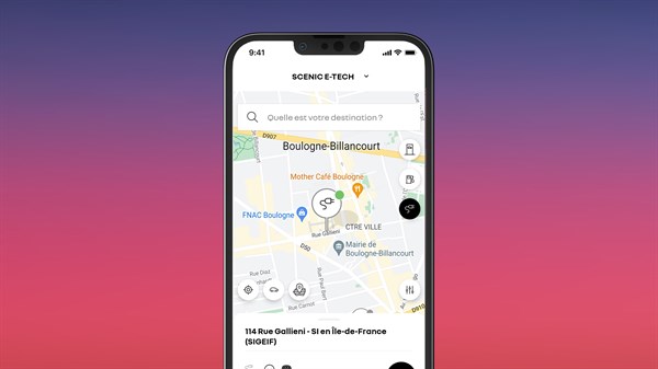 Pametni telefon s aplikacijom My Renault na zaslonu, koji prikazuje kartu s pretraživanjem punionica za vozilo Renault Scenic E-Tech electric.
