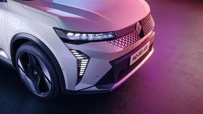Prednji dio vozila Renault Scenic E-Tech electric u bijeloj boji s naglašenom LED svjetlosnom trakom i detaljima maske, na ružičasto-ljubičastoj pozadini.
