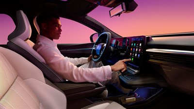 Vozač u unutrašnjosti vozila Renault Scenic E-Tech electric upravlja velikim središnjim openR link zaslonom osjetljivim na dodir, dok je kabina osvijetljena ružičasto-ljubičastim svj