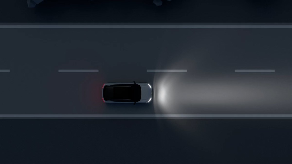 Vozilo prikazano odozgo vozi noću cestom, s osvijetljenim snopom prednjih svjetala ispred.