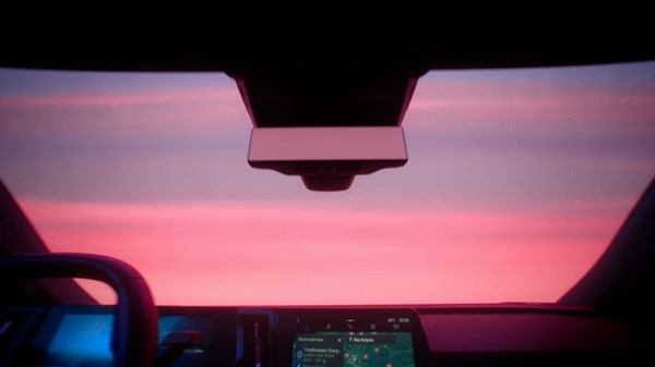 Pogled kroz prednje vjetrobransko staklo iz unutrašnjosti vozila Renault Scenic, s ružičastim nebom pri zalasku sunca.
