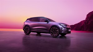 Renault Scenic u bočnom profilu na mokroj obalnoj površini pri zalasku sunca, s ružičastim nebom, morem i stijenama u pozadini.