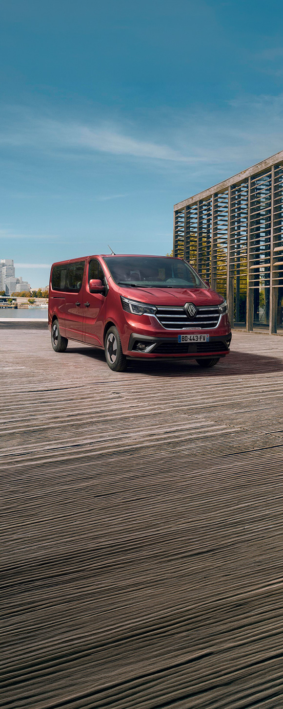  Vozilo Trafic Passenger parkirano uz urbani pejzaž, prikazano u Carmine Red boji.