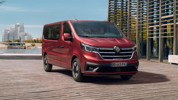 Vozilo Trafic Passenger parkirano uz urbani pejzaž, prikazano u Carmine Red boji.

