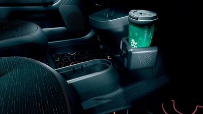 Unutrašnjost vozila Renault Twingo s detaljem središnje konzole, držačem za čašu s napitkom zelene ambalaže i pretincima za odlaganje između prednjih sjedala.