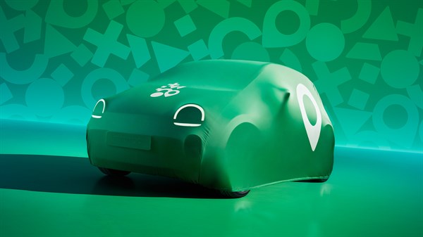 Vozilo Renault Twingo E-Tech electric prekriveno zaštitnom navlakom u zelenoj boji s grafičkim uzorkom, parkirano u studijskom okruženju.