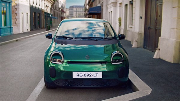Zeleni Renault Twingo E-Tech electric prikazan sprijeda na gradskoj ulici između zgrada.